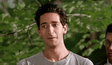 a man in a gray shirt looks at the camera
