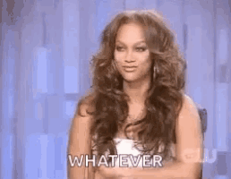 a woman with long hair is sitting in a chair with her hands folded and says whatever .