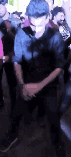 a man with blue hair is dancing in a crowd at a party