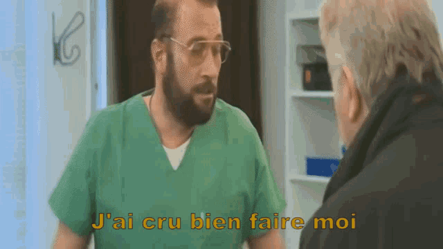 a man in a green scrub is talking to another man and the words j'ai cru bien faire moi are visible