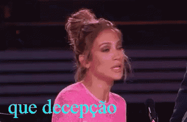 a woman in a pink shirt is sitting in front of a microphone and the words que decepcao are behind her