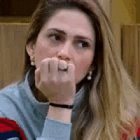 a woman is covering her mouth with her hand while wearing a ring .