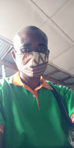 a man wearing a green shirt and an orange collar is wearing a mask