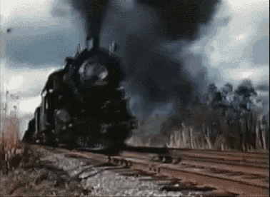 a train is going down the tracks and smoke is coming out of it .