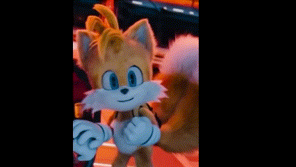 a close up of tails from sonic the hedgehog standing next to a person in a dark room .