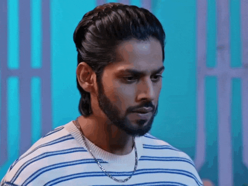 a man with a beard is wearing a striped shirt and a chain .