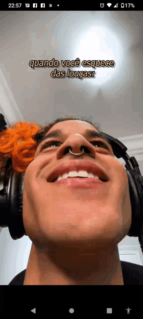 a man wearing headphones and a nose ring is smiling with the time 22:57