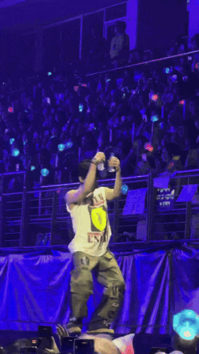a man in a wu tang shirt is dancing on stage