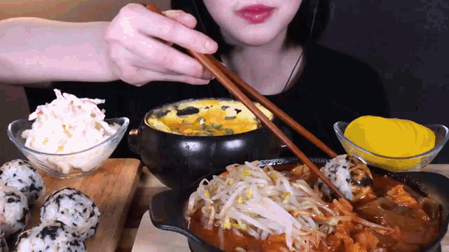 a woman is eating food with chopsticks and a bowl of rice balls