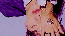 a man with a tattoo on his hand is laying on his back with his head down .