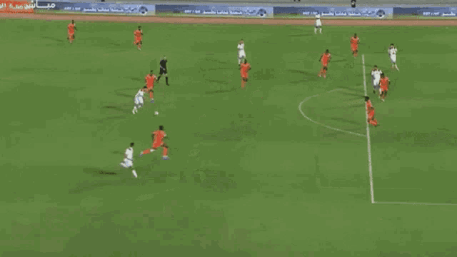 a soccer game is being played on a field with arabic writing on the side