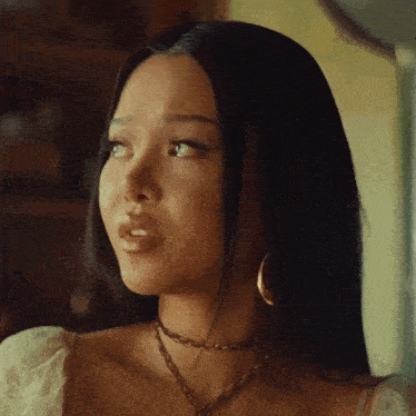 a woman wearing a choker and hoop earrings looks to her left