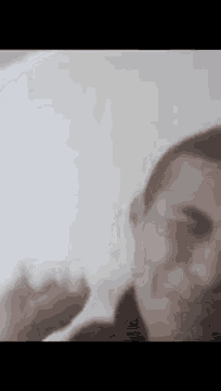 a close up of a man 's face with a hand behind it .