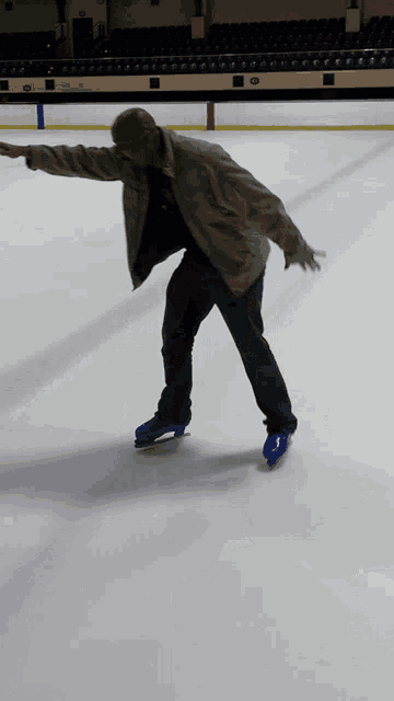 a man in a jacket is ice skating on a rink with his arms outstretched