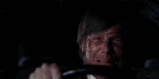 a man is driving a car at night with a light behind him