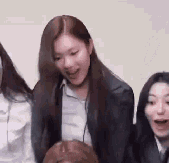 a group of women are sitting next to each other in a room . one of the women is wearing a suit and tie .