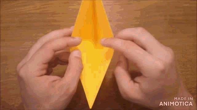 a person is making an origami crane with a yellow paper