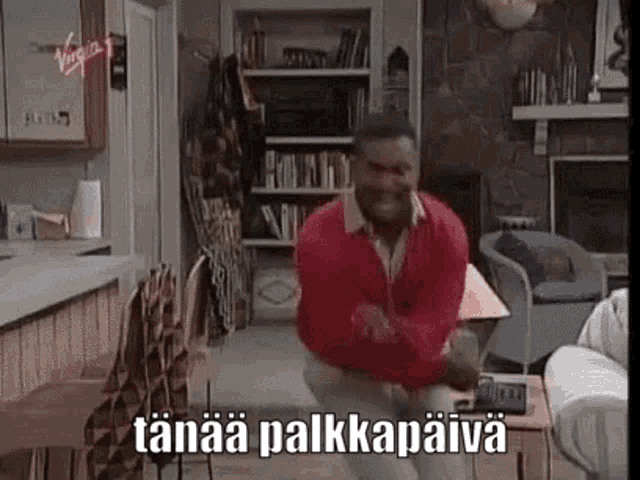 a man in a red sweater is dancing in a living room with the words taanaa palkkamaiva written on the screen .
