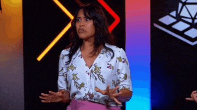 a woman in a floral shirt and pink skirt is standing in front of a colorful background .