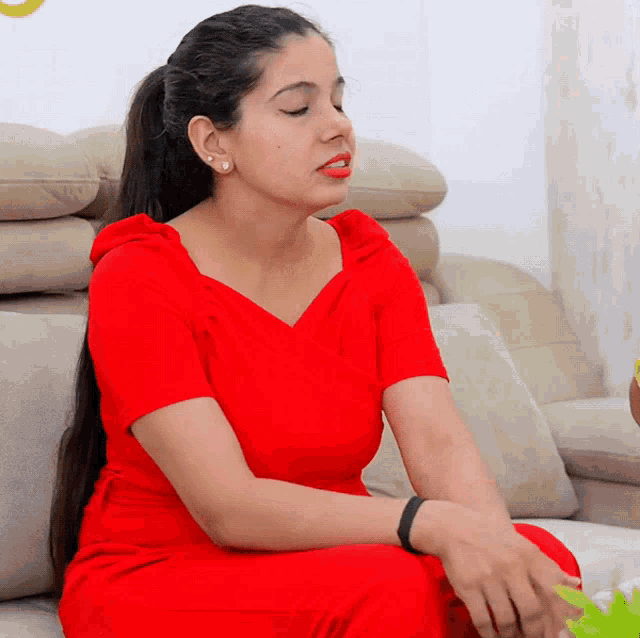 a woman in a red dress sits on a beige couch