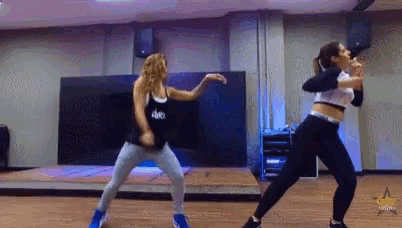 two women are dancing in a dance studio and one of them is wearing a shirt that says dance