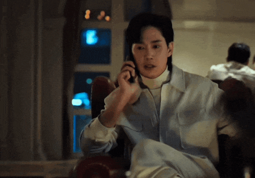 a man is sitting in a chair talking on a phone