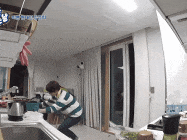 a man in a striped sweater is standing in a kitchen with a sign above him that says ' a ' on it