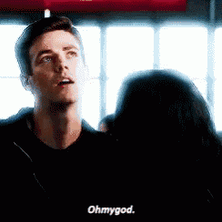 a man in a black shirt is talking to a woman in a room .