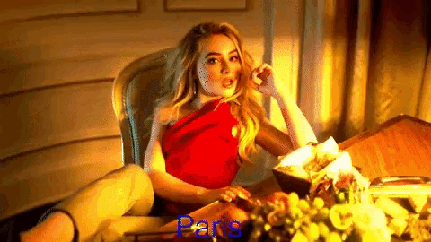 a woman in a red dress is sitting at a table with paris written on the bottom of the image