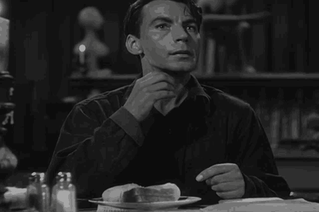 a man is sitting at a table with a plate of food and a salt and pepper shaker