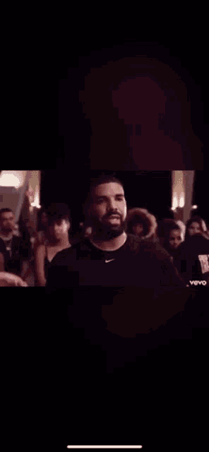 a man with a beard is standing in front of a crowd of people and waving at them .