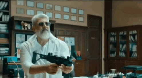 a man with a beard and sunglasses is holding a gun in his hand .