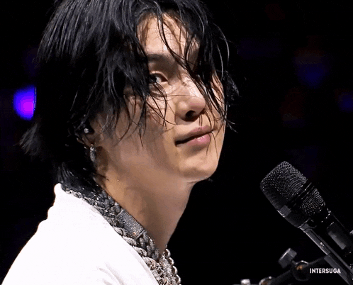 a close up of a person in front of a microphone with the words intersuga visible