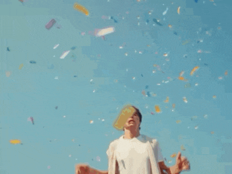 a man is standing in front of a blue sky with confetti flying around him .