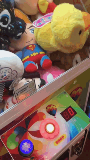 a stuffed superman is in a box next to a drop machine
