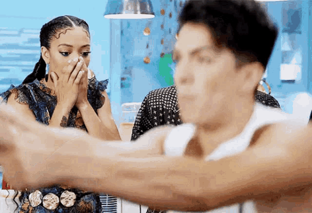 a woman is covering her mouth while looking at a man 's arm