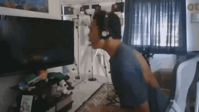 a man wearing headphones is playing a video game in front of a television