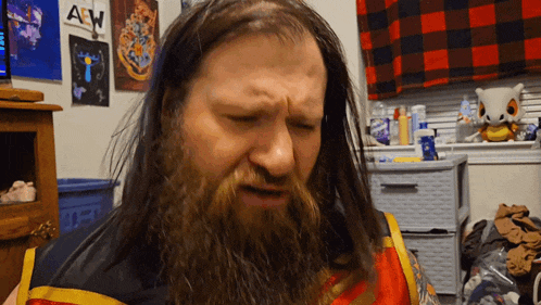 a man with a beard is sitting in front of a wall that has a sign that says aw on it