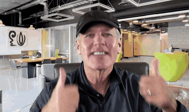 a man in a hat gives a thumbs up