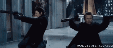 a man and a woman are holding guns in their hands in a hallway .