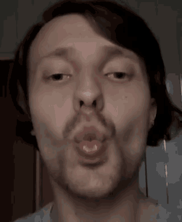 a man with a beard and mustache is blowing a kiss .