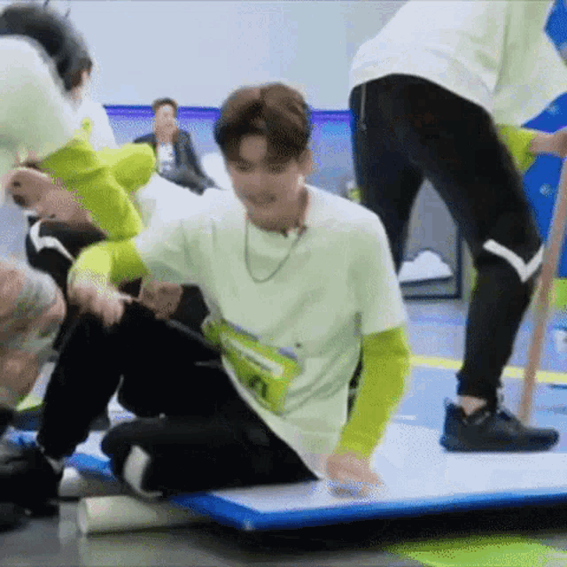 a group of people are playing a game while a man is sitting on a mat .