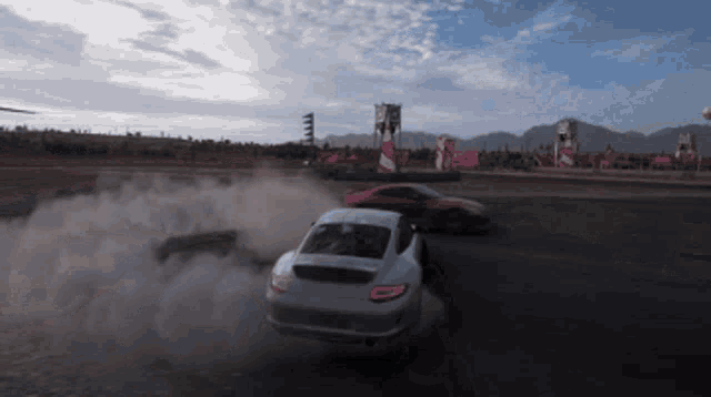 a few cars are drifting on a track with smoke coming out of the back