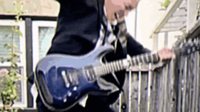 a man is playing a blue electric guitar on a balcony