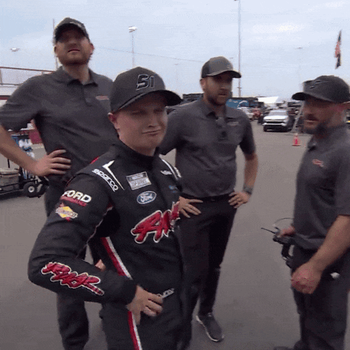 a man wearing a black ford shirt stands in a parking lot