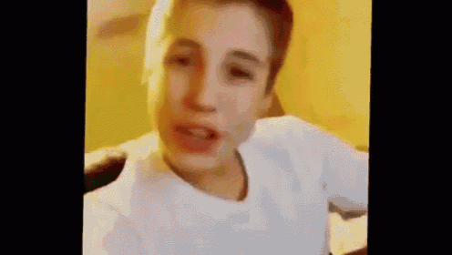 a young boy in a white shirt is making a funny face in a video .