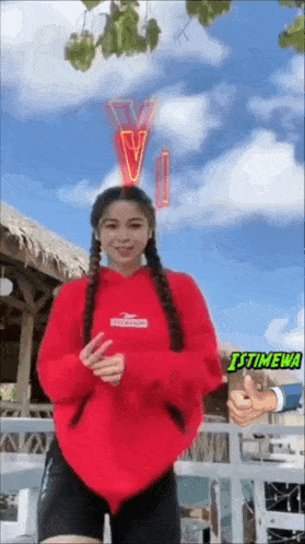 a woman in a red hoodie is giving a thumbs up .