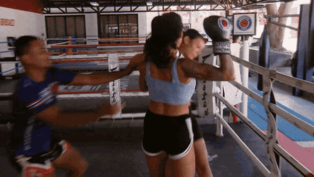 two women are boxing in a ring with a sign that says ' fighting ' on it