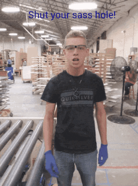 a man in a quiksilver shirt stands in a factory