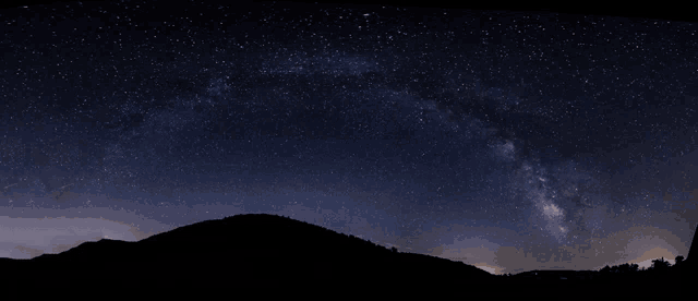 a night sky filled with lots of stars with a mountain in the foreground